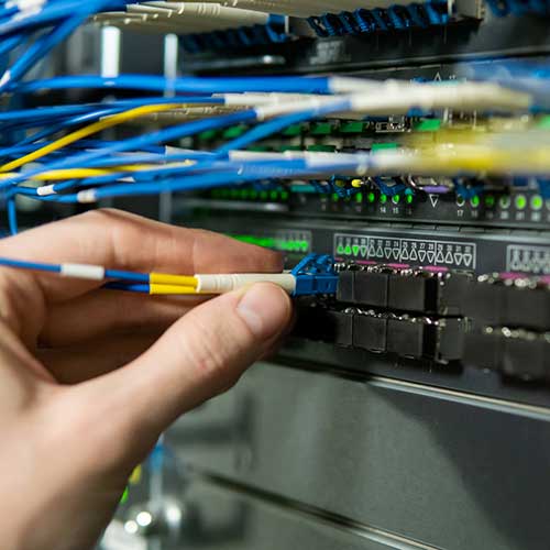 Tekniker som patchar in en fiberkabel i en internet switch